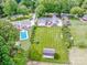 Expansive aerial view featuring a home with a pristine lawn, pool, mature trees, and outbuildings at 195 Brookfield Cir, Mooresville, NC 28115