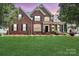Brick home features a well-manicured front lawn, tasteful landscaping, and a covered front porch at 212 Forest Walk Way, Mooresville, NC 28115