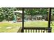 Backyard features a charming swing set with colorful chairs amidst green lawn and trees at 217 Eighth Ave, New London, NC 28127