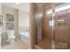 Bright bathroom with a tub, toilet, glass-enclosed shower, and neutral tile throughout at 3211 Gilroy Dr, Fort Mill, SC 29707