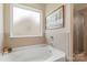 Relaxing bathtub area with a soaking tub, tiled walls, and natural light streaming through the window at 3211 Gilroy Dr, Fort Mill, SC 29707