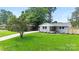 Exterior shot of a cozy home with a spacious, well-kept lawn and mature tree coverage at 4042 Uppergate Ln, Charlotte, NC 28215
