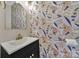 Charming powder room featuring designer wallpaper, a black vanity, a white vessel sink, and a gold faucet at 413 Hurston Cir, Charlotte, NC 28208