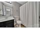 Neutral bathroom showcasing a vanity, toilet, and tiled shower with a patterned shower curtain at 413 Hurston Cir, Charlotte, NC 28208