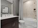 Modern bathroom featuring a tub-shower combo, vanity with a sink, dark cabinets and neutral walls at 5517 Swaling St, Charlotte, NC 28217