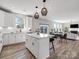 Bright, white kitchen features an island, ample counter space, and pendant lighting, seamlessly flowing into the dining and living areas at 6012 Millbridge Pkwy, Waxhaw, NC 28173