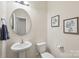Bathroom featuring a pedestal sink, toilet, mirror, and tasteful decorations at 6315 Prosperity Church Rd, Charlotte, NC 28269