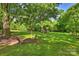 This backyard offers a firepit with a large green lawn and beautiful, mature trees at 6624 Lancer Dr, Charlotte, NC 28226