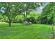 A sprawling backyard with a lush green lawn, mature trees, and a chicken coop at 6624 Lancer Dr, Charlotte, NC 28226