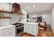 Modern kitchen featuring white cabinets, stainless steel appliances, and a stylish range hood at 6624 Lancer Dr, Charlotte, NC 28226