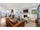 Open-concept living area with hardwood floors, a brick fireplace, and comfortable leather sofa at 6624 Lancer Dr, Charlotte, NC 28226