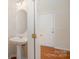 Bathroom featuring a pedestal sink, wood flooring, and white door at 6948 Church Wood Ln, Huntersville, NC 28078