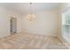 Elegant dining room featuring neutral carpet, a decorative chandelier, and a bright window at 6948 Church Wood Ln, Huntersville, NC 28078
