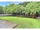 Large, green backyard featuring mature trees and lush grass, enclosed by a white picket fence at 7544 Rolling Meadows Ln, Huntersville, NC 28078