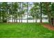Expansive backyard with lush lawn and tall trees leading to the tranquil lake waters at 8216 Malibu Pointe Ln, Denver, NC 28037