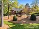 Beautifully landscaped front yard of a brick home with mature trees and a circular driveway at 961 Confederate Ave, Salisbury, NC 28144