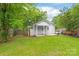 Cozy home backyard with a covered porch, lush green lawn, privacy fence, and mature trees at 104 Willetta Dr, Charlotte, NC 28217