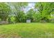Expansive backyard featuring a storage shed, mature trees, and a lush green lawn at 104 Willetta Dr, Charlotte, NC 28217