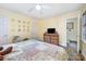 Bedroom with ceiling fan, adjacent bath, stained glass window, and natural wood dresser at 1115 Grovewood Dr, Charlotte, NC 28208
