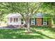 Charming brick home with well-maintained lawn, complemented by mature trees and an American flag display at 1115 Grovewood Dr, Charlotte, NC 28208