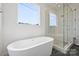 Elegant bathroom with freestanding tub and glass-enclosed shower, illuminated by a large window at 13605 Tranquil Day Dr, Matthews, NC 28105