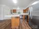 A modern kitchen featuring stainless steel appliances, wooden cabinets, an island, and hardwood flooring at 14056 Lyon Hill Ln, Huntersville, NC 28078