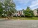 Exterior view of townhomes featuring manicured lawns, colorful front doors, and mature trees at 14056 Lyon Hill Ln, Huntersville, NC 28078