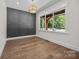 Stylish bedroom with wood floors, modern light fixture, decorative wall trim, and a large window at 1408 Bloomsberry Ln, Waxhaw, NC 28173