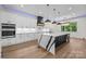 Modern kitchen featuring a large island with waterfall countertops, stainless steel appliances, and custom lighting at 1408 Bloomsberry Ln, Waxhaw, NC 28173