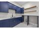 Well-appointed laundry room with navy blue cabinets, quartz countertops, designer tile, and wooden shelving at 1408 Bloomsberry Ln, Waxhaw, NC 28173