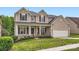 Charming two-story home features a welcoming front porch, manicured lawn, and attached two-car garage at 1455 Moss Creek Dr, Harrisburg, NC 28075
