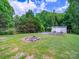Wide backyard with a fire pit, shed, and potential garden area surrounded by trees at 2020 White Cedar Ln, Waxhaw, NC 28173