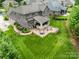 Aerial view of a gray brick home showing patio and fire pit in large, green backyard at 320 Eden Hollow Ln, Weddington, NC 28104