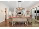 Dining room features a modern chandelier, a farmhouse-style table, and a view into the living room at 320 Eden Hollow Ln, Weddington, NC 28104