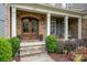 Inviting front porch with stone steps, a decorative double-door entry, and comfortable seating area at 320 Eden Hollow Ln, Weddington, NC 28104