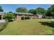 Traditional brick home with lush lawn, mature trees, and an American flag at 3400 Barfield Dr, Charlotte, NC 28217