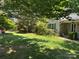 A spacious front yard featuring a green lawn with mature trees and a small house at 401 Overlook Dr, Monroe, NC 28110