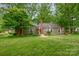 Exterior elevation showing the yard, brick chimney, green siding, and white trim at 408 Idlewood Dr, Kannapolis, NC 28083