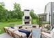 Inviting back patio featuring a brick fireplace with a TV, comfortable seating, and a lush green lawn at 4174 Charlton Rd, Fort Mill, SC 29715