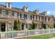 Attractive brick townhome displaying dormers, black shutters, landscaping, and a white picket fence at 4313 Courtly Ln, Belmont, NC 28012