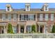 Brick townhome showcasing dormers, black shutters, landscaping, and a white picket fence at 4313 Courtly Ln, Belmont, NC 28012