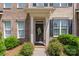 Charming brick townhome featuring a decorative front door, black shutters, and manicured landscaping at 4313 Courtly Ln, Belmont, NC 28012