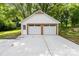 Detached two-car garage with white doors and trim, complemented by a concrete driveway and lush landscaping at 437 Chadmore South Dr, Charlotte, NC 28270