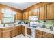 Traditional eat-in kitchen with wood cabinets, white appliances, and a tile floor at 4424 Huntington Dr, Gastonia, NC 28056
