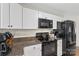 A functional kitchen featuring granite counters, black appliances, and white cabinets for a modern cooking experience at 4916 Ritchie Rd, Lincolnton, NC 28092