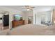 Bright main bedroom with ceiling fan, dresser with TV, and doorway leading to kitchen at 4916 Ritchie Rd, Lincolnton, NC 28092