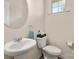 Bathroom featuring a pedestal sink, toilet, circular mirror, and a window providing natural light at 5014 Forest Hills Pl, Fort Mill, SC 29707