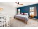 Bedroom showcasing a bed, crib, hardwood side tables, and a blue accent wall creating a soothing space at 5014 Forest Hills Pl, Fort Mill, SC 29707