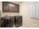 Laundry room featuring dark washer and dryer set with upper cabinets and electrical panel at 5014 Forest Hills Pl, Fort Mill, SC 29707