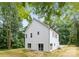 Back exterior view of a modern, white house surrounded by lush greenery and blue sky at 515 Dixie Dr, Mooresville, NC 28115